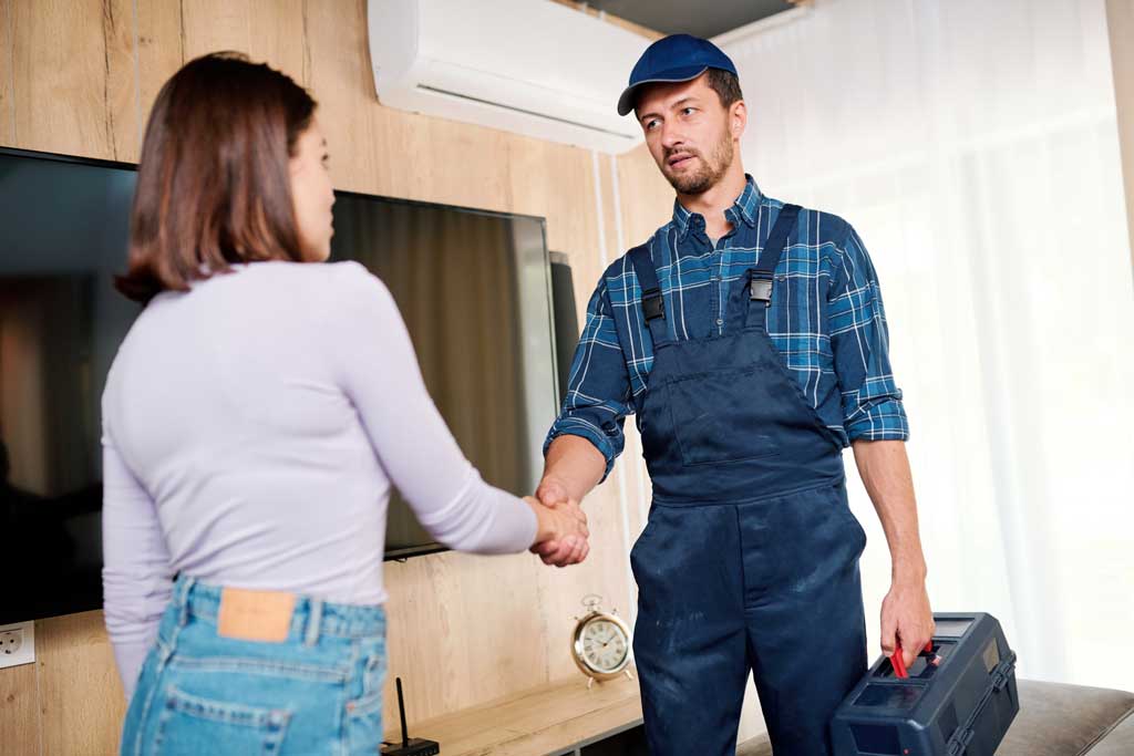 A homeowner shaking hands with the HVAC contractor after HVAC installation in their living room